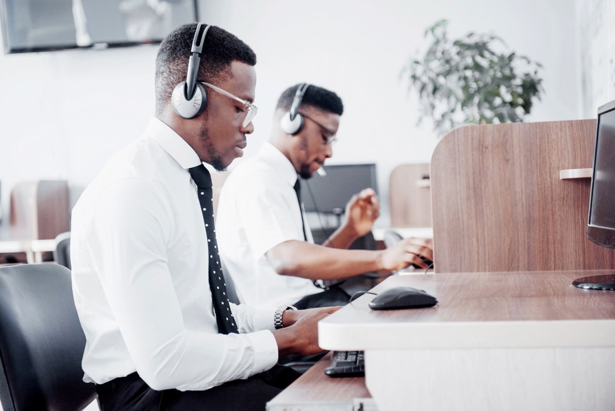 African american customer support operator with hands-free headset working in the office.